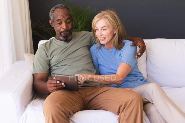 Різні старші пари сидять на дивані і використовують цифровий планшет. перебування вдома в ізоляції під час карантину . — стокове фото