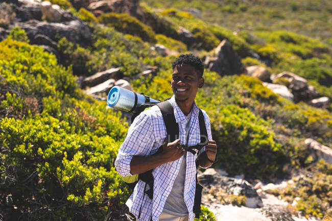 Portrait of fit happy african american man hiking outdoors to camera. fitness training and healthy outdoor lifestyle. — Stock Photo