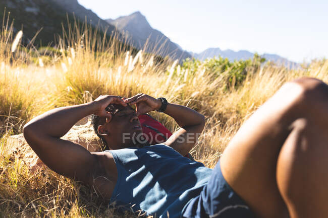 Afro-americano exercitando ao ar livre descansando em uma montanha. treinamento de fitness e estilo de vida saudável ao ar livre. — Fotografia de Stock