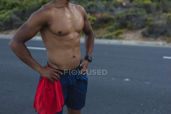 Mittelteil eines fitten afrikanisch-amerikanischen Mannes, der auf einer Küstenstraße im Freien trainiert. Fitnesstraining und gesunder Lebensstil im Freien. — Stockfoto