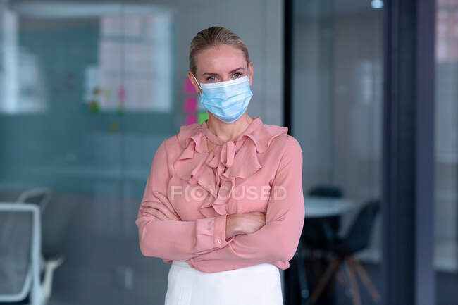 Porträt einer kaukasischen Geschäftsfrau mit Gesichtsmaske und digitalem Thermometer. Geschäftsmann bei der Arbeit im modernen Büro während der Covid 19 Coronavirus-Pandemie. — Stockfoto