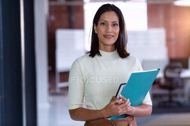 Porträt einer glücklichen Geschäftsfrau mit gemischter Rasse im Besitz von Dokumenten. Geschäftsmann bei der Arbeit im modernen Büro. — Stockfoto