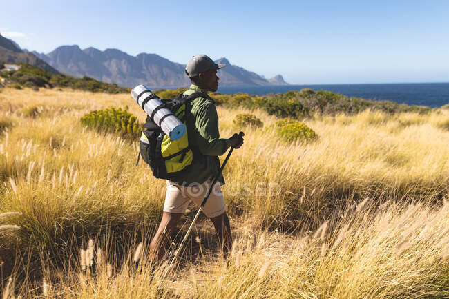 Африканський американець, який ходить надворі, користуючись палицями на горі. Тренування фітнесу і здоровий спосіб життя на вулиці. — стокове фото