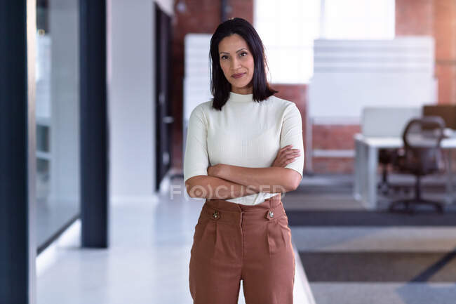 Portrait of smiling mixed race businesswoman with hands crossed. business person at work in modern office. — Stock Photo