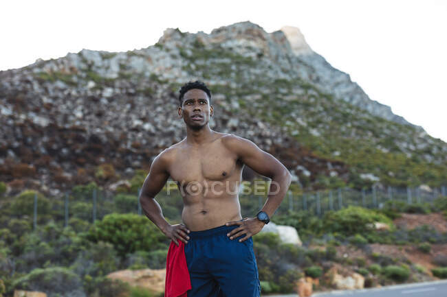 Ritratto di uomo afroamericano in forma che si esercita all'aperto su una strada costiera. allenamento fitness e stile di vita sano all'aperto. — Foto stock