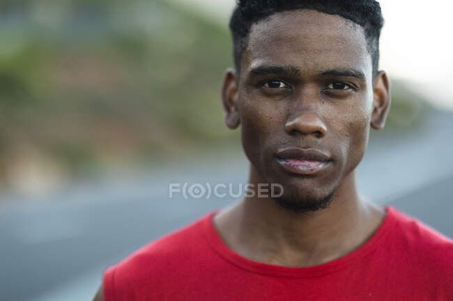 Portrait of fit african american man exercising outdoors on a coastal road to camera. fitness training and healthy outdoor lifestyle. — Stock Photo