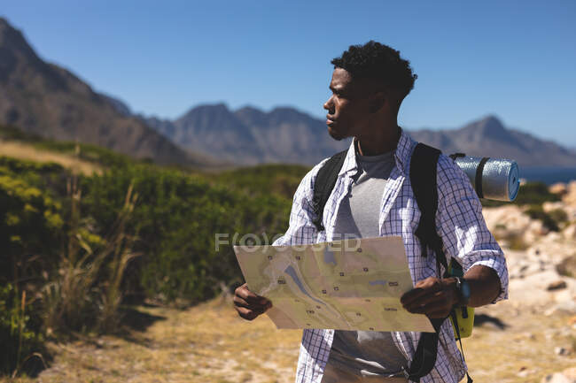 Afrikanischer Mann beim Sport im Freien beim Lesen einer Landkarte auf einem Berg. Fitnesstraining und gesunder Lebensstil im Freien. — Stockfoto