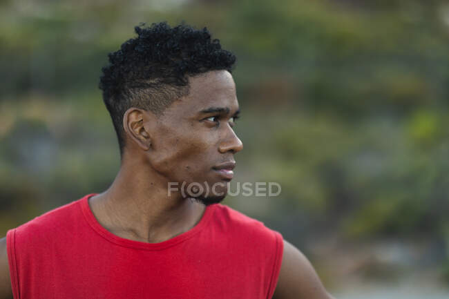 Portrait d'un homme afro-américain en forme faisant de l'exercice à l'extérieur regardant vers un côté sur une route côtière. entraînement physique et mode de vie sain en plein air. — Photo de stock