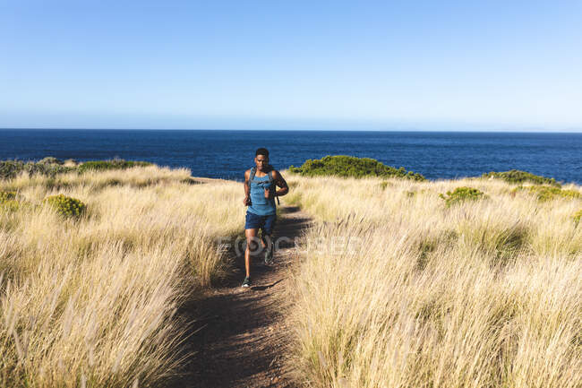Uomo afroamericano che si allena all'aperto correndo su una montagna. allenamento fitness e stile di vita sano all'aperto. — Foto stock