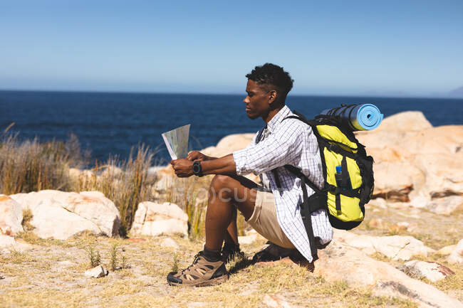 Afrikanisch-amerikanischer Mann, der im Freien Landkarten auf einem Berg liest. Fitnesstraining und gesunder Lebensstil im Freien. — Stockfoto