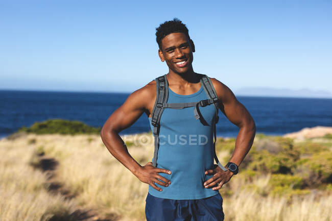 Retrato de hombre afroamericano feliz en forma haciendo ejercicio al aire libre a la cámara. entrenamiento de fitness y estilo de vida saludable al aire libre. - foto de stock