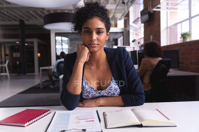 Mixed race businesswoman sitting at desk with documents having video call. independent creative design business. — Stock Photo