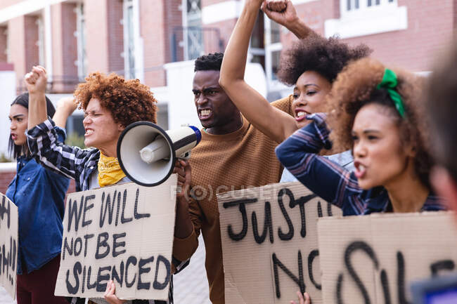 Протестующие мужчины и женщины маршируют с плакатами протеста, кричат и используют мегафон. Демонстрация равных прав и справедливости во время ковида 19 пандемии коронавируса. — стоковое фото