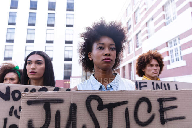 Three diverse male and female protesters on march holding homemade protest signs looking away. equal rights and justice demonstration march. — Stock Photo