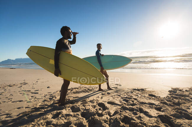 Feliz casal afro-americano na praia carregando pranchas de surf. tempo de lazer ao ar livre saudável pelo mar. — Fotografia de Stock