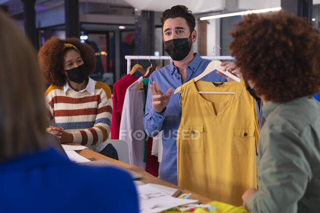 Diverse group of creative colleagues wearing face masks brainstorming in meeting room. independent creative design business during covid 19 coronavirus pandemic. — Stock Photo