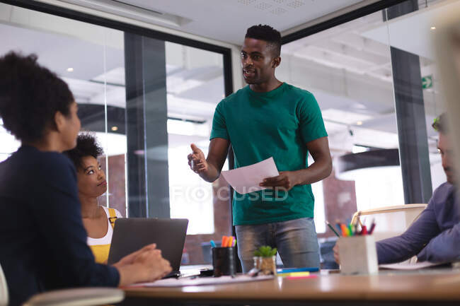 African american man giving speech to diverse group of colleagues in meeting room. independent creative design business. — Stock Photo