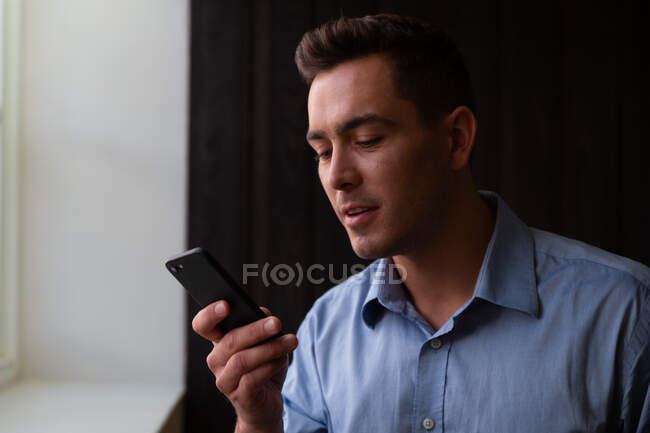 Портрет усміхненого стильного кавказького бізнесмена з використанням смартфона. бізнесмен на роботі в сучасному офісі . — стокове фото
