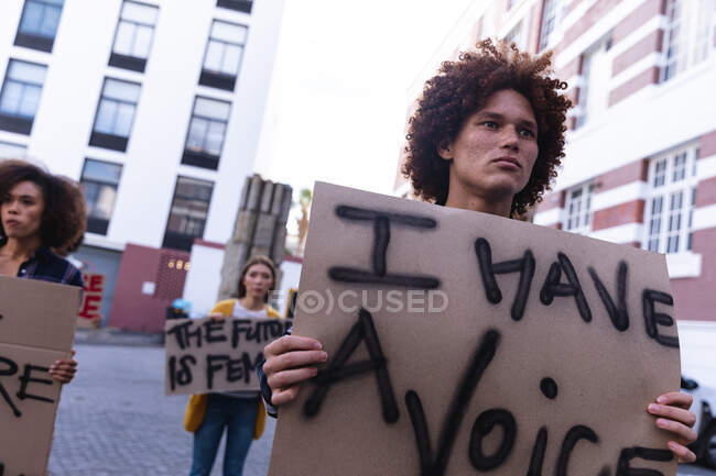 Manifestant mixte masculin en marche tenant un signe de protestation fait maison. manifestation pour l'égalité des droits et la justice. — Photo de stock
