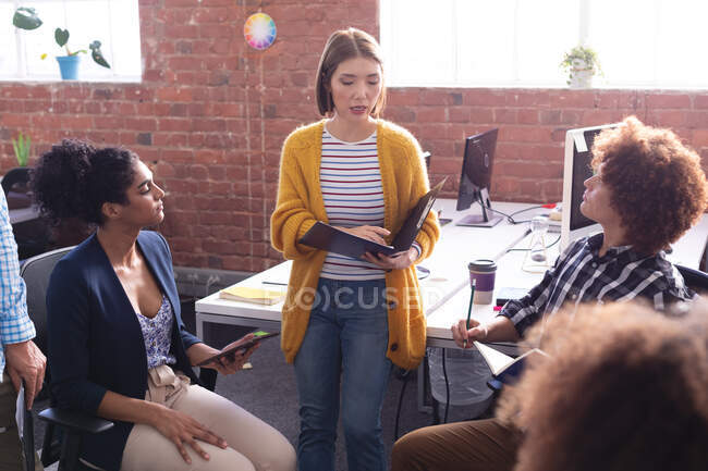 Asian businesswoman reading documents speaking to diverse group of colleagues at work. independent creative design business. — Stock Photo