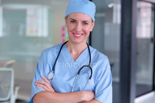 Portrait of smiling caucasian female doctor wearing scrubs and stethoscope. medical professional at work during coronavirus covid 19 pandemic. — Stock Photo