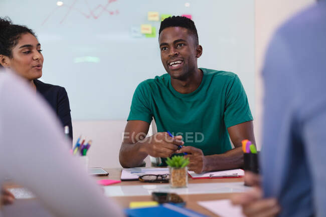 Homem afro-americano falando com diversos grupos de pessoas na sala de reuniões. negócio de design criativo independente. — Fotografia de Stock