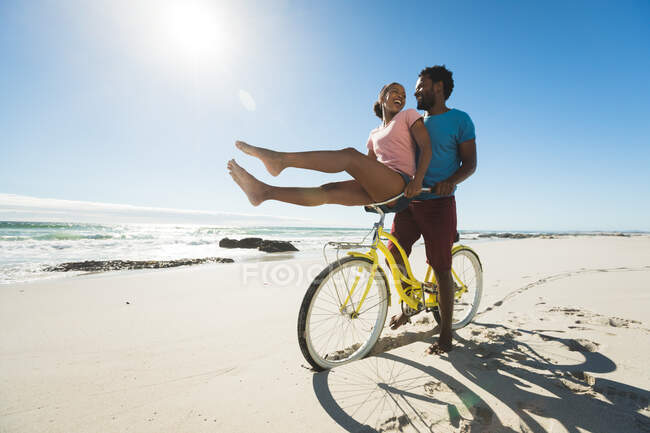 Glückliches afrikanisch-amerikanisches Paar auf Fahrrädern am Strand. gesunde Freizeit im Freien am Meer. — Stockfoto