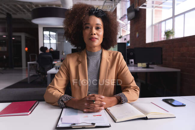 Африканська бізнесменка-американка сидить за столом з документами, що мають відеодзвінок. Незалежний бізнес творчого дизайну. — стокове фото