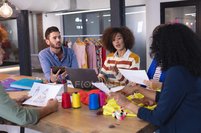 Diverse group of fashion designer colleagues in discussion at work using digital tablet and laptop. independent creative design business. — Stock Photo