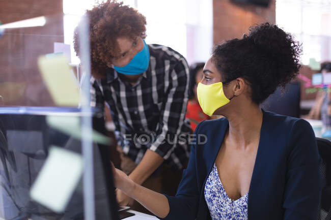 Mélange de race masculine et féminine portant des masques dans la discussion au travail. entreprise indépendante de conception créative pendant la pandémie de coronavirus covid 19. — Photo de stock