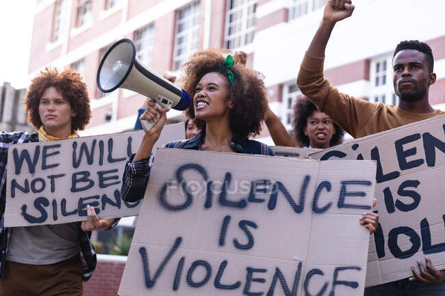 Diverse männliche und weibliche Demonstranten auf dem Marsch halten Protestschilder hoch, recken Fäuste und setzen Megafone ein. Demonstrationszug für Gleichberechtigung und Gerechtigkeit. — Stockfoto
