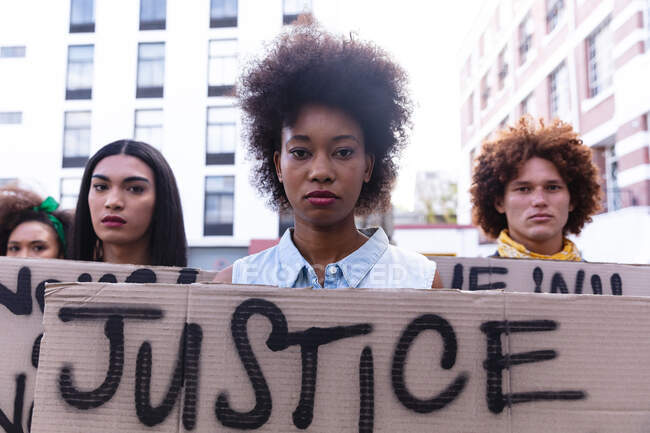 Drei unterschiedliche männliche und weibliche Demonstranten auf dem Marsch, die selbstgebastelte Protestschilder in die Kamera halten. Demonstrationszug für Gleichberechtigung und Gerechtigkeit. — Stockfoto