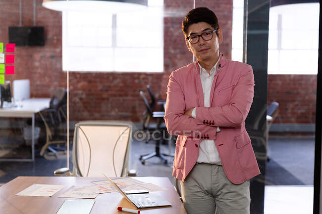 Ritratto di elegante uomo d'affari asiatico con le braccia incrociate guardando alla fotocamera. uomo d'affari al lavoro in ufficio moderno. — Foto stock