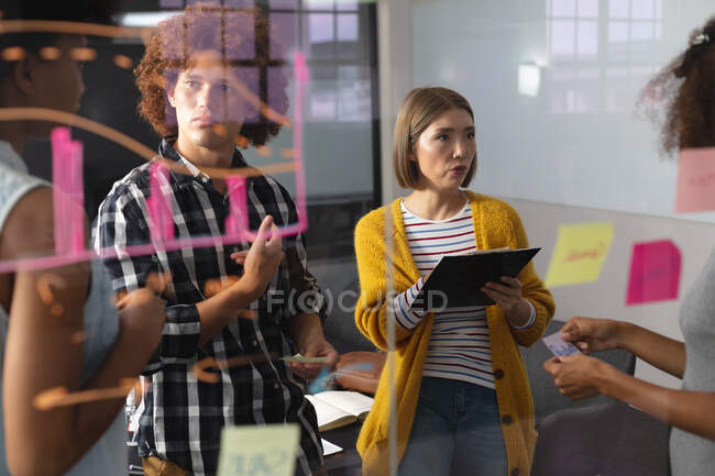 Diverso grupo de colegas creativos haciendo una lluvia de ideas en la sala de reuniones tomando notas. negocio independiente de diseño creativo. - foto de stock