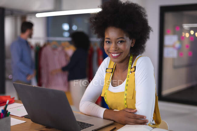 Retrato de mujer afroamericana diseñadora de moda usando cinta métrica de sastre sonriendo para la cámara. negocio independiente de diseño creativo. - foto de stock