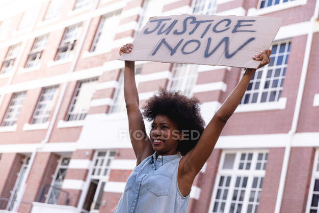 African american female protester on march holding a homemade protest sign above her head smiling. equal rights and justice demonstration march. — Stock Photo