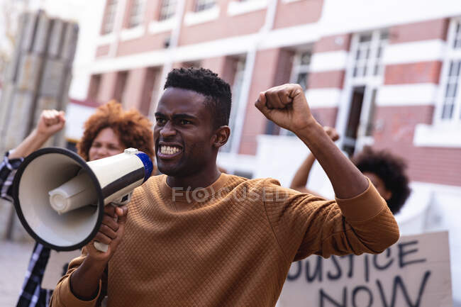 Uomo afroamericano che usa il megafono con manifestanti in marcia con cartelli e pugni alzati. marcia per la parità di diritti e la giustizia. — Foto stock