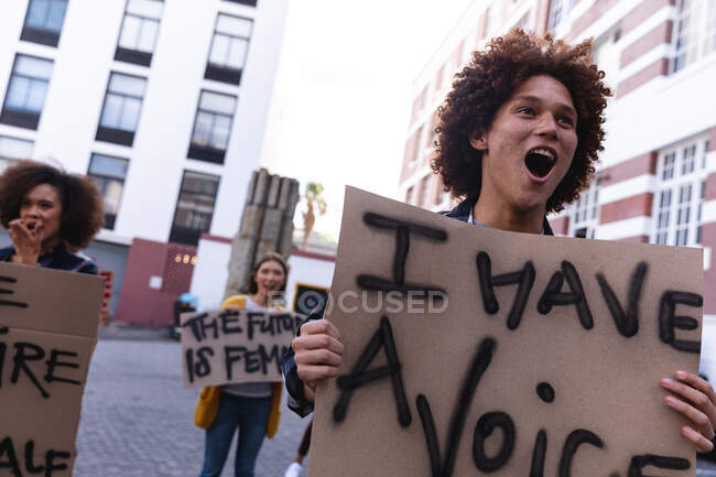 Manifestant mixte masculin en marche tenant un signe de protestation fait maison et criant. manifestation pour l'égalité des droits et la justice. — Photo de stock