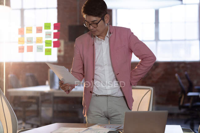 Портрет стильного азіатського бізнесмена, що стоїть за столовими читаннями. Бізнесмен на роботі в сучасному офісі.. — стокове фото
