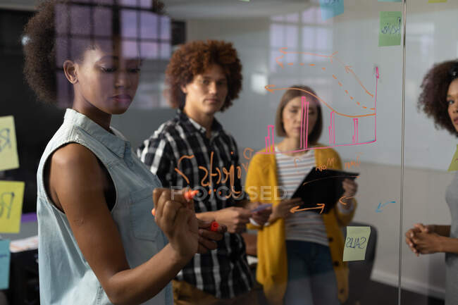 Grupo diverso de colegas criativos brainstorming escrever notas na parede de vidro na sala de reuniões. negócio de design criativo independente — Fotografia de Stock