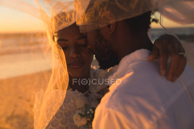 Африканская влюбленная пара выходит замуж, обнимается на пляже во время заката. любовь, романтика и свадебный пляжный отдых. романтика и отдых на пляже. — стоковое фото