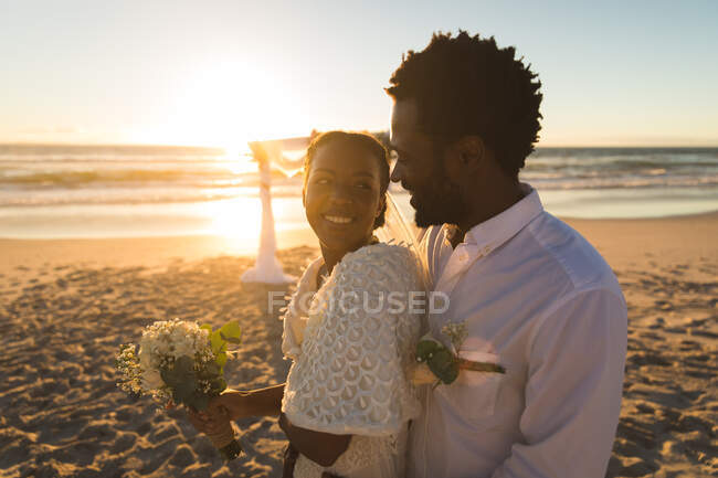 Coppia afroamericana innamorata di sposarsi, sorridente sulla spiaggia durante il tramonto. amore, romanticismo e matrimonio vacanza al mare vacanza estiva. — Foto stock