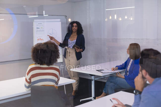 Empresária afro-americana no quadro branco dando apresentação a diversos grupos de colegas. negócio de design criativo independente. — Fotografia de Stock