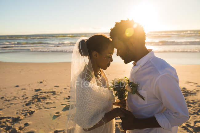 Casal afro-americano apaixonado por casar-se na praia a tocar nas testas. amor, romance e férias de verão na praia. — Fotografia de Stock