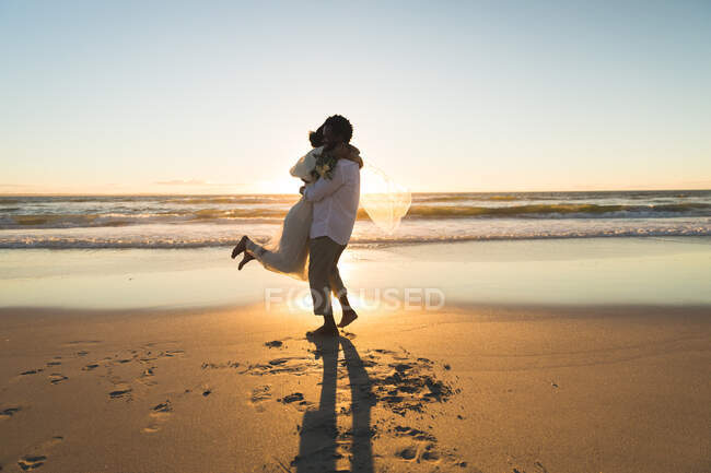 Coppia afroamericana innamorata di sposarsi, abbracciarsi sulla spiaggia durante il tramonto. amore, romanticismo e matrimonio vacanza al mare vacanza estiva. — Foto stock