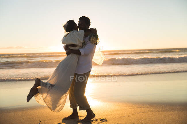 Couple afro-américain amoureux se marier, embrasser sur la plage pendant le coucher du soleil. amour, romance et mariage plage pause vacances d'été. — Photo de stock