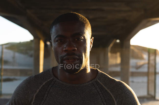 Portrait of african american man exercising outdoors on bridge at sunset. healthy outdoor lifestyle fitness training. — Stock Photo