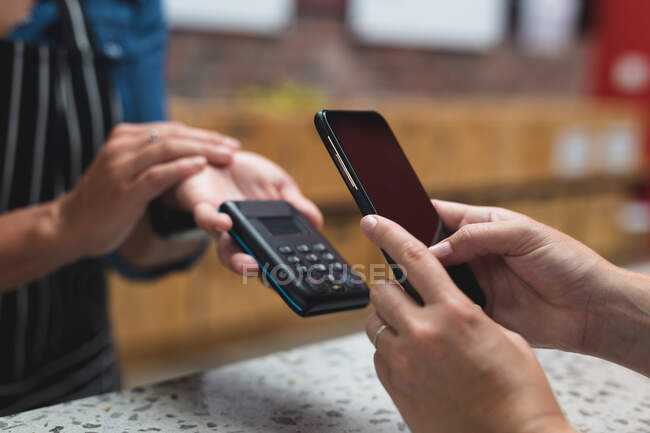 Midsection of woman making contactless phone payment over counter at gym. fitness and leisure time at gym during coronavirus covid 19 pandemic. — Stock Photo
