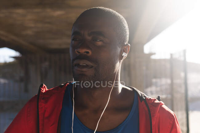 Портрет африканского американца, занимающегося спортом на открытом воздухе, в наушниках, слушающего музыку. фитнес-тренировки. — стоковое фото