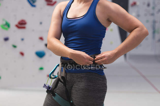 Milieu de la femme se préparant à l'escalade au mur d'escalade intérieur. fitness et temps libre au gymnase. — Photo de stock
